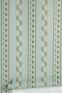 the wall paper is green and white with small designs on it, as well as an ornamental design