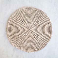 a round woven placemat on a white marble countertop, with the center circle made out of straw