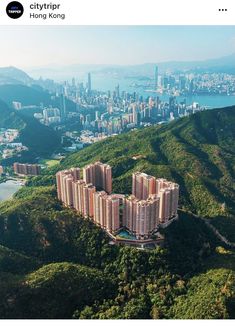 an aerial view of a city with mountains in the foreground and a body of water below