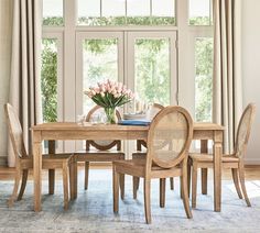 a dining room table and chairs in front of a large window with flowers on it