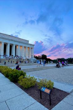 the lincoln memorial at dusk with people walking and sitting on benches in front of it