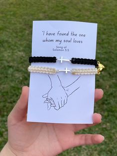 a person holding up a card with a cross on it and two bracelets attached to it