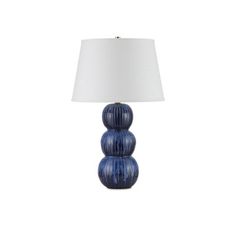 a lamp that is sitting on top of a white table cloth next to a blue vase