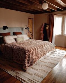 a large bed sitting in the middle of a bedroom on top of a hard wood floor