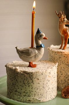 two cakes with frosting and animals on them, one has a candle in the shape of a duck