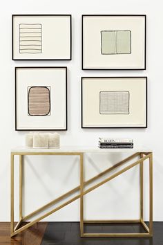 four framed art pieces hang on the wall above a table