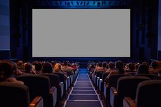 an auditorium with people sitting in rows watching a movie on the big screen at night