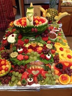 a table topped with lots of different types of fruits and veggies on top of metal trays