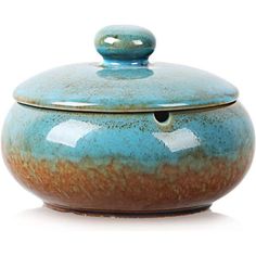 a large blue and brown pot with a lid on the top, sitting in front of a white background