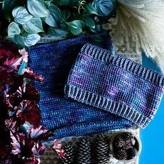 a pile of knitted items sitting on top of a table next to some flowers