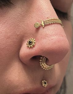 a close up of a person's nose with piercings on it and an earring