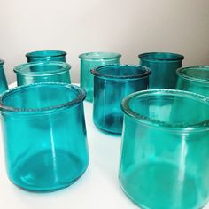 several blue glass jars sitting on top of a white table next to eachother