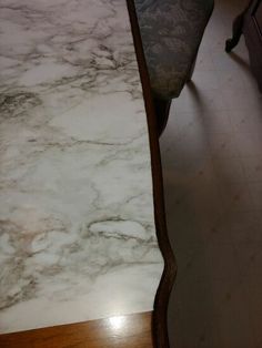 a marble counter top in a kitchen next to a wooden table with drawers on it