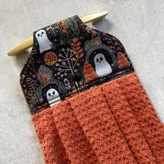 an orange and black towel with two ghost faces on it, sitting next to a pair of scissors