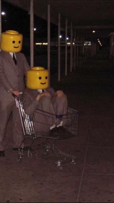 a man in a suit pushing a shopping cart with two legos on his head