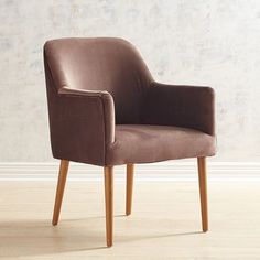 a brown chair sitting on top of a hard wood floor next to a white wall