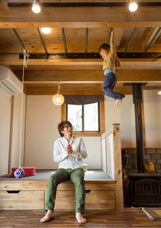 a man sitting on top of a wooden bench next to a boy hanging upside down