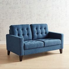 a blue couch sitting on top of a hard wood floor next to a white wall