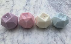 four different colored candles sitting on top of a marble counter