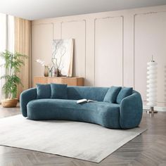 a blue couch sitting on top of a white rug in a living room next to a window