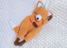 an orange stuffed animal laying on top of a white blanket with the words pattern written below it