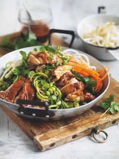 a bowl filled with meat and veggies on top of a wooden cutting board