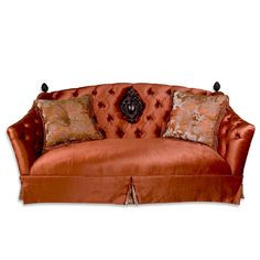 an orange couch with decorative pillows on it's arm and back, against a white background