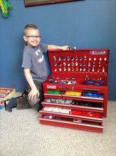 a young boy sitting in front of a red tool box