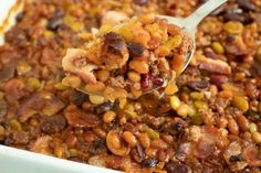 a spoon full of beans and meat in a casserole dish