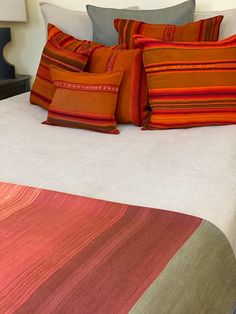 a bed with orange and red pillows on top of it