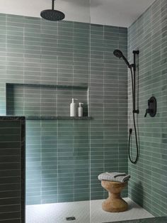 a bathroom with green tiled walls and flooring, including a shower head in the corner