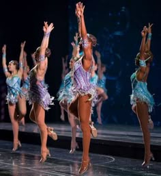 the dancers are performing on stage with their hands in the air