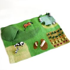 a green rug with toy farm animals on it and grass in the foreground is a white background