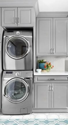 a laundry room with gray cabinets and washer and dryer