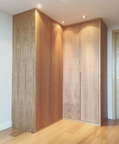 an empty room with wooden cabinets and hard wood flooring on the side, along with white walls