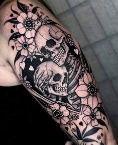 a woman's arm with a skull and flowers on it