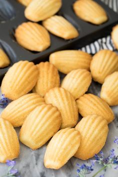 there are many cookies in the trays on the table with lavender sprinkled around them