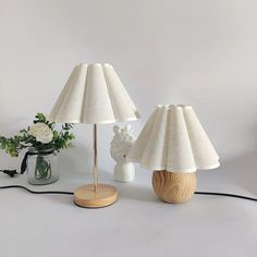 two lamps are sitting on a table next to a vase with flowers and a teddy bear