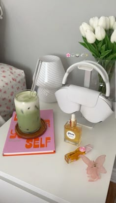 a white table topped with a vase filled with flowers next to a candle and other items