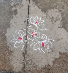 the sidewalk is painted with white and red designs on it's concrete, which has been decorated with flowers