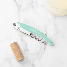 a bottle opener sitting on top of a marble counter next to a corkscrew