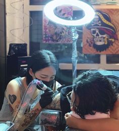 two women sitting next to each other in front of a mirror with lights on it