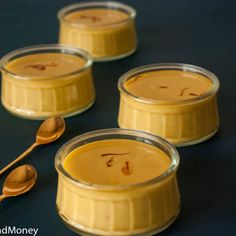 four small jars filled with pudding and spoons on a blue tablecloth next to each other