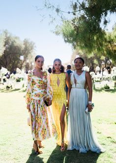 three women standing next to each other in dresses