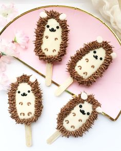 four cupcakes made to look like hedgehogs on a pink platter