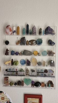 a shelf filled with lots of different types of rocks on it's sides next to a framed photograph