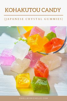 colorful gummy bears sitting on top of a table next to a glass bowl filled with jelly