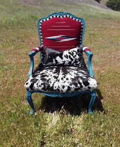 a cow print chair sitting on top of a lush green field