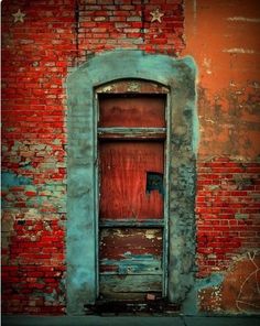 an old door is open in front of a red brick wall