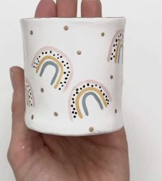 a hand holding up a cup with a rainbow design on the outside and polka dots on the inside